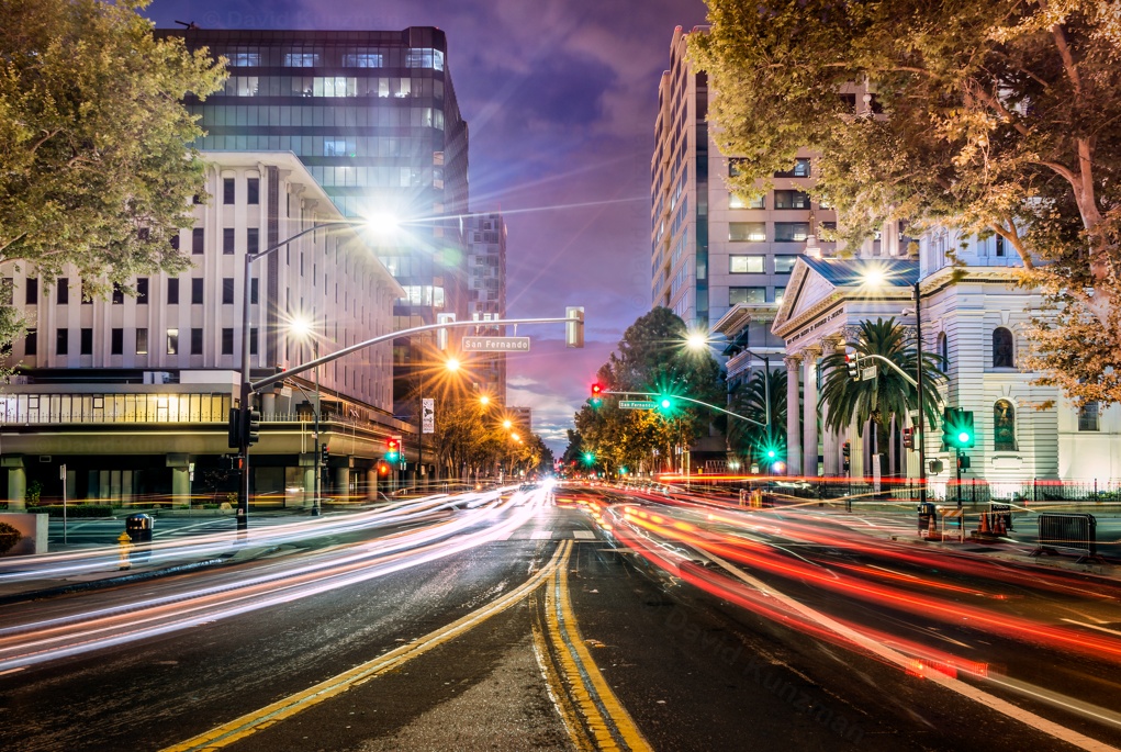 A long exposure photograph looking down Market Street in downtown San Jose, California.  The lights from passing cars create light trails floating just above the street.